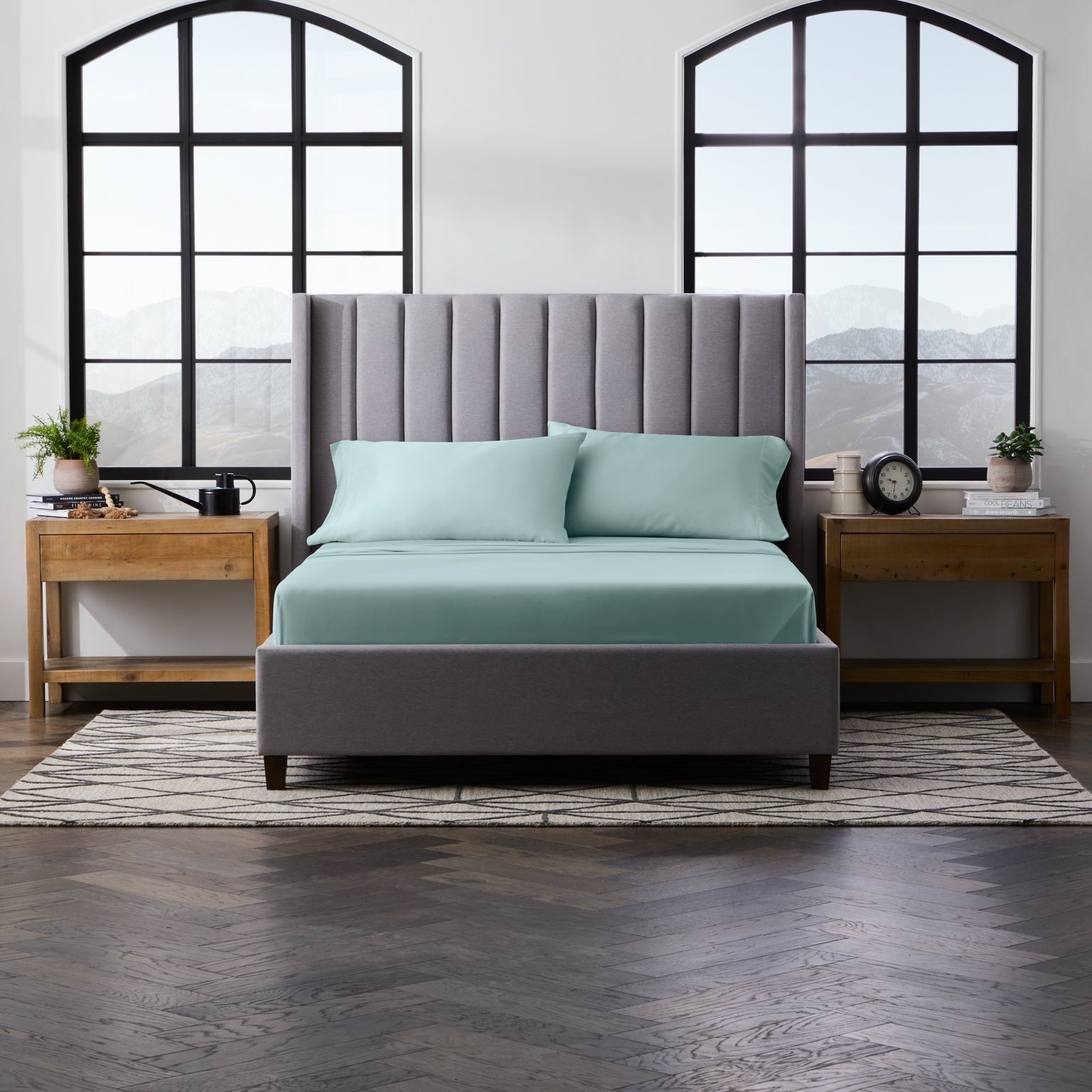 Bedroom with a gray upholstered bed, light blue bedding, and wooden nightstands
