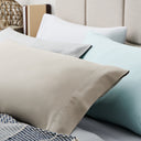 Close-up of beige, white, and light blue pillows on a bed.