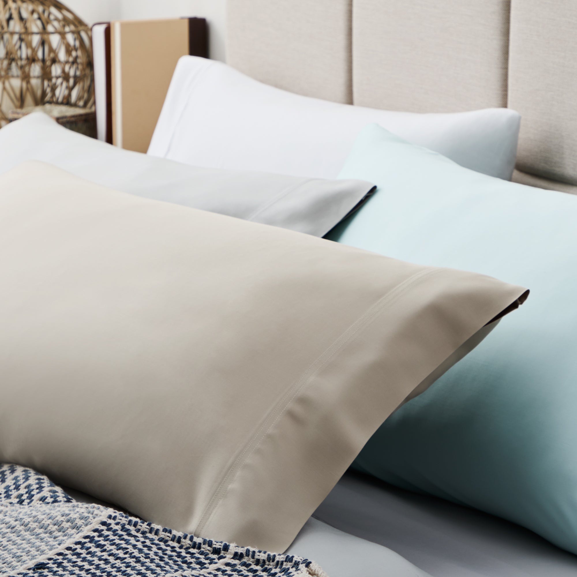 Close-up of beige, white, and light blue pillows on a bed.